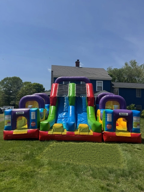 Colorful inflatable slide and obstacle combo set up in a sunny Connecticut backyard